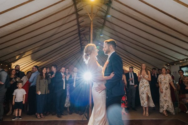 Bride and groom dance with guests surrounding them first dance