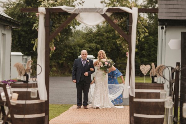 Bride and father walk down the aisle flowers in hand