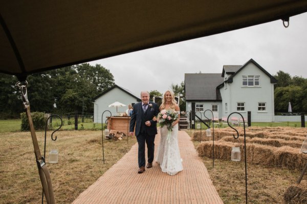 Bride and father walk down the aisle flowers in hand