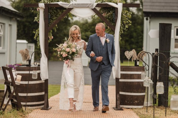 Bride and father walk down the aisle flowers in hand