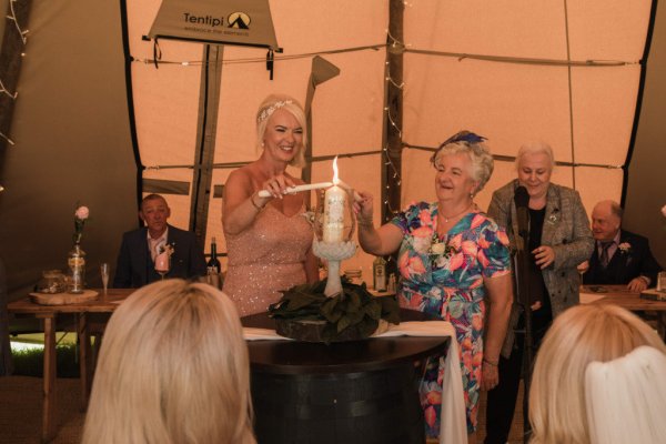 Two mothers lighting candles at alter