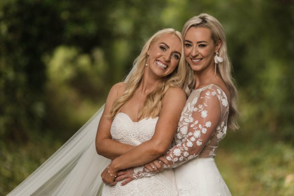 Bride and bride embrace hug in park/forest