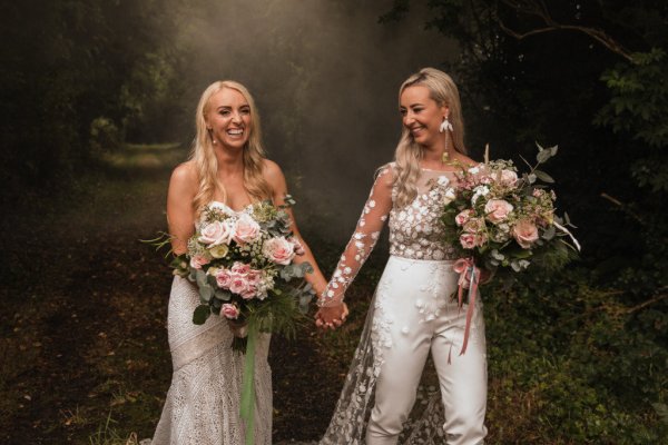 Bride and bride dress detail standing in forest holding hands