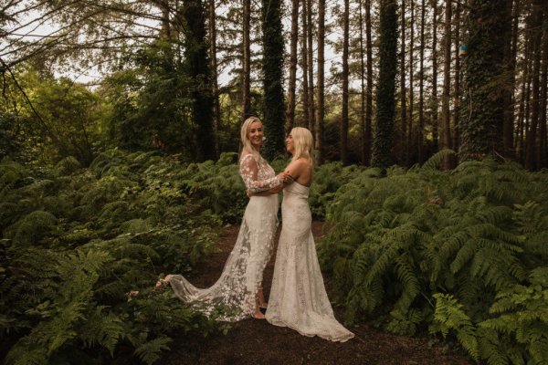 Bride and bride dress detail standing in forest hugging