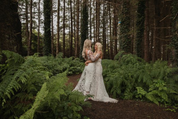 Bride and bride dress detail standing in forest hugging