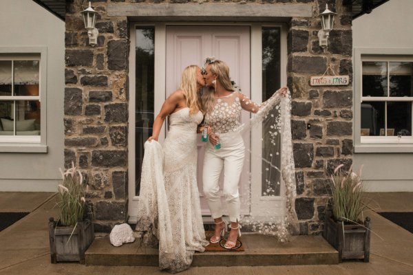 Bride and bride kissing in front of white door