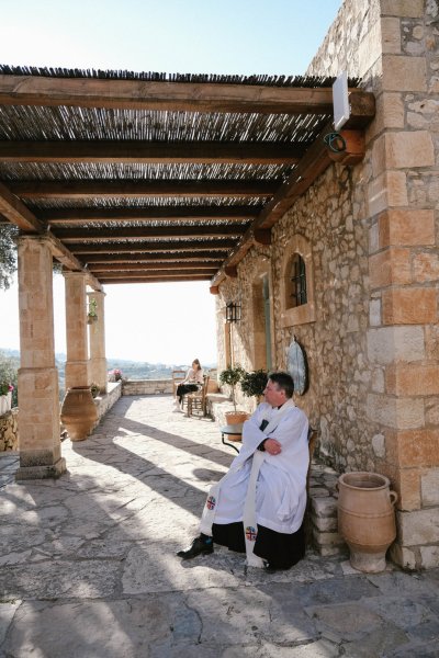 Priest sits and admires Greek view landscape