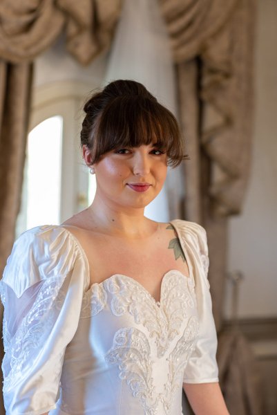 Bride stands and poses for camera in bedroom