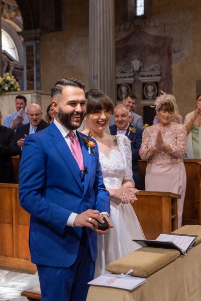 Bride and groom smile along with guests in background