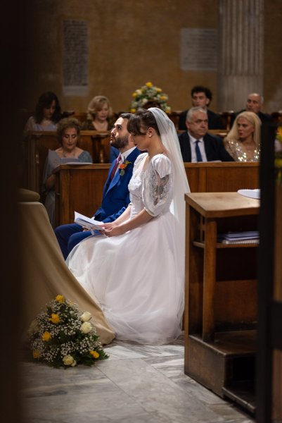 Bride and groom sitting at alter looking at vows