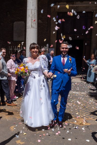 Bride and groom confetti being thrown over them by guests