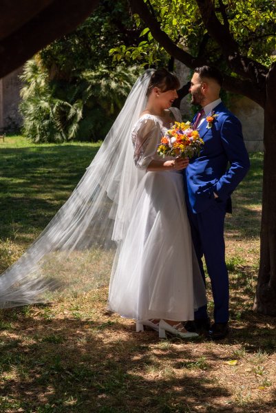 Bride and groom standing in park garden facing each other