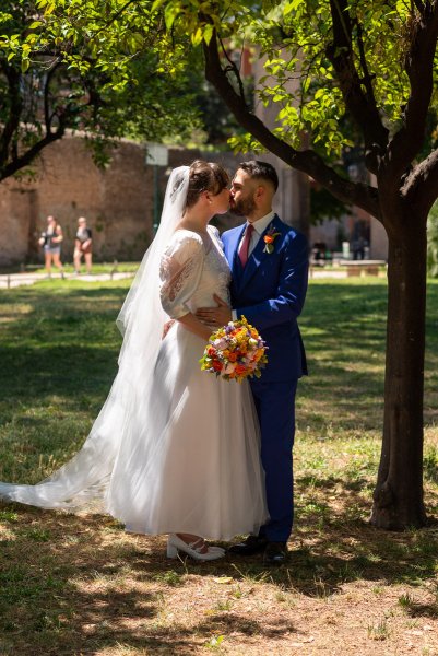 Bride and groom standing in park garden kissing kiss