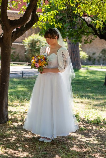 Bride on her own standing in garden looking down