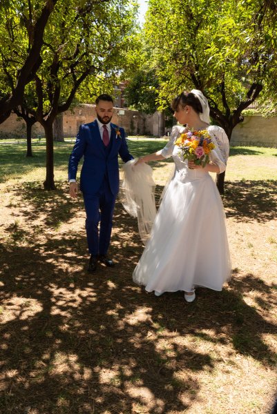 Bride and groom standing in park garden hand in hand holding hands