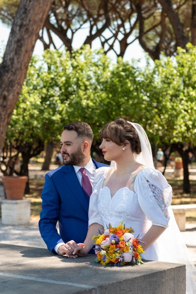 Bride and groom look away from camera in park