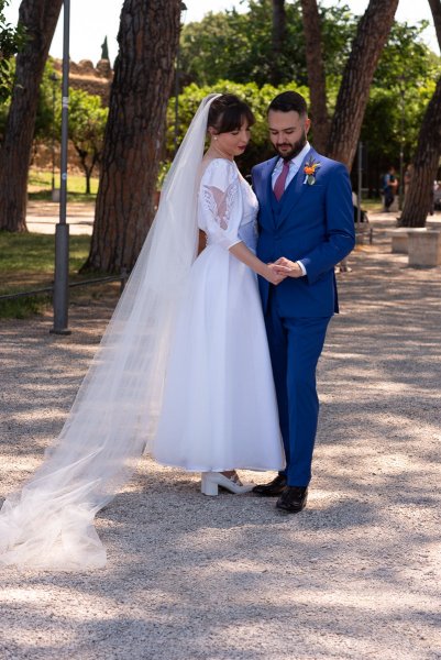 Bride and groom hold hands on pathway in park