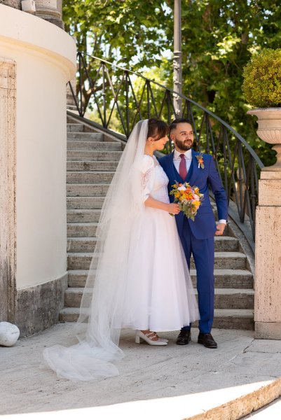 Bride and groom exterior garden holding bouquet of flowers stairs in background