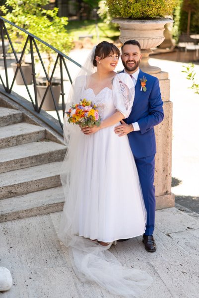 Bride and groom exterior garden holding bouquet of flowers stairs in background