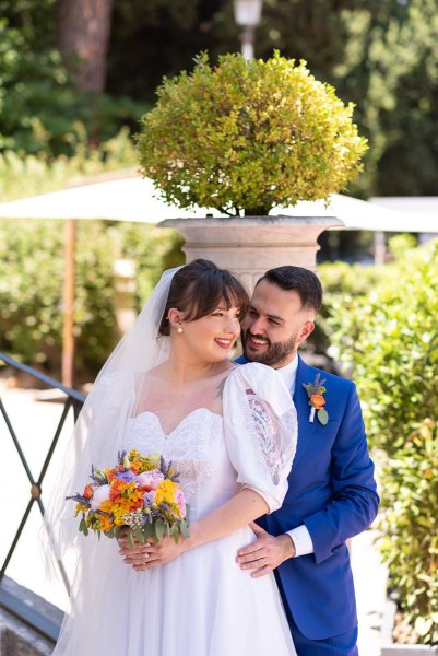 Bride and groom exterior garden holding bouquet of flowers