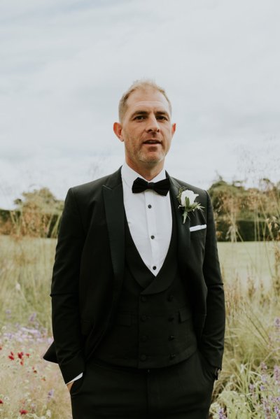 Groom in hayfield standing on his own