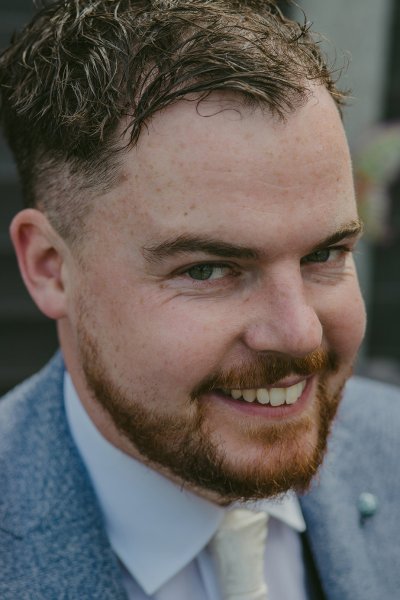 Groom in suit smiles for the camera