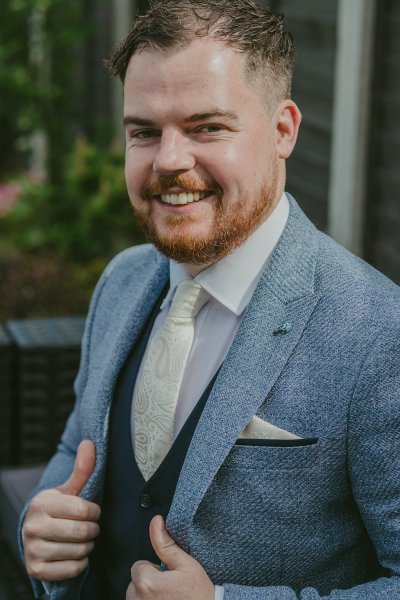 Groom in suit smiles for the camera