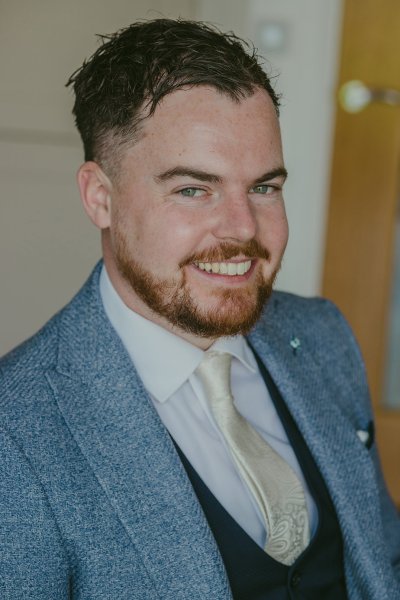 Groom in suit smiles for the camera