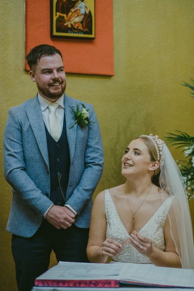 Bride and groom priest sign marriage certificate smiling