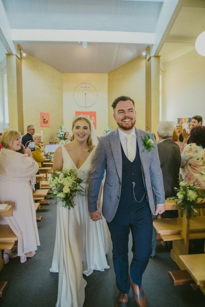 Bride and groom at church alter just wed holding hands smiling