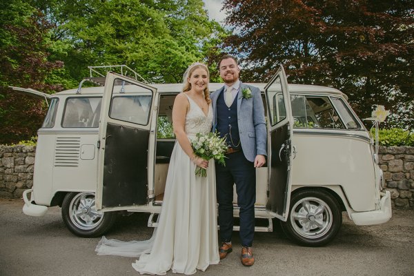 Bride and groom standing outside white wedding car