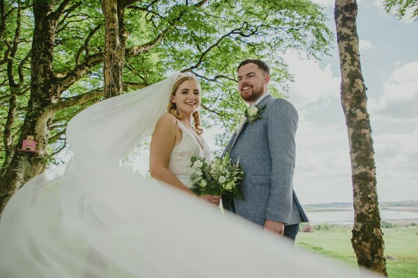 Veil blowing in the wind bride and groom forest setting