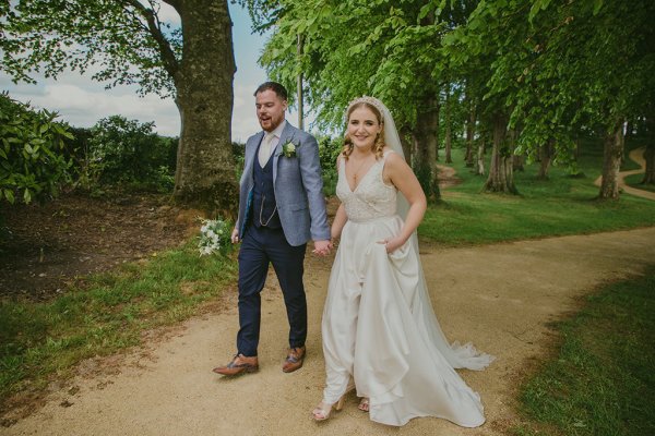 Couple bride and groom walking through forest/park hand in hand