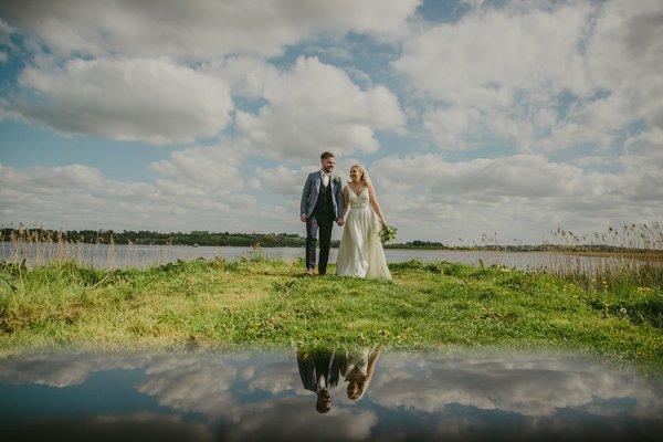 Sky cloud reflection on glass stone monument and bride and groom flowers