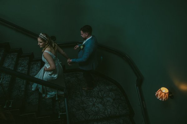 Bride and groom walk down the staircase together