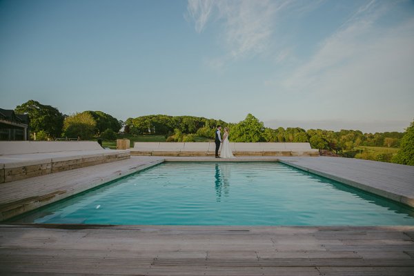 Bride and groom standing beside hotel swimming pool