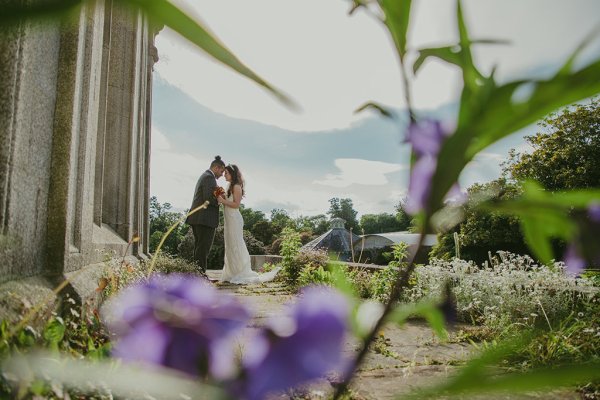 Purple flowers in foreground couple bride and groom in background