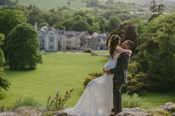 Killruddery house wedding venue in background groom picks up bride on grass