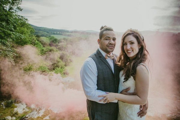 Bride and groom embrace hug in garden setting pink smoke in background