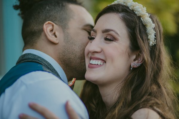 Bride laughing smiling groom kisses her on the cheek