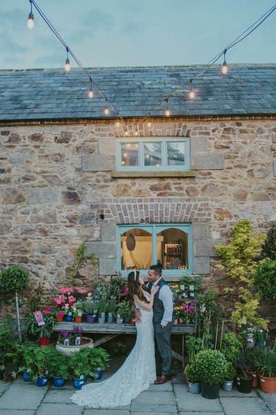 Bride and groom stand in garden pots and plants detail window