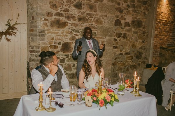 Man reading from book during speech and groom bride laughing