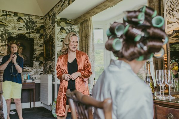 Bridesmaid wearing orange satin bridalwear and bride wearing curlers in hair