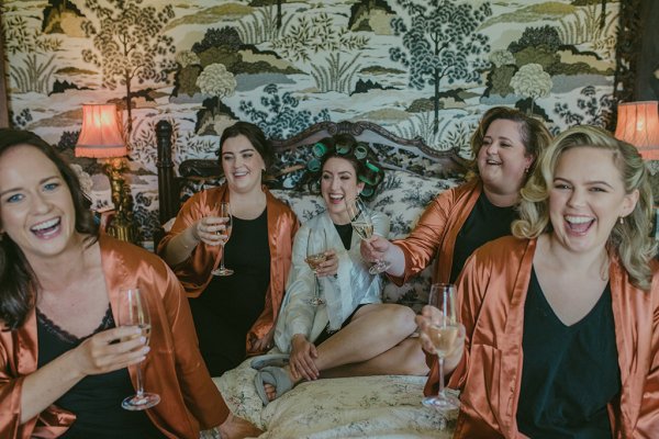 Bridesmaids and bride in orange bridalwear drinking champagne/prosecco