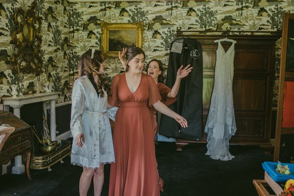 Bridesmaid and bride get ready bridal dress hangs up