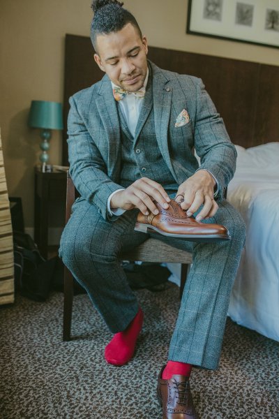 Groom putting on brown brogue wedding shoes