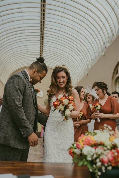 Bridesmaid groom and bride orange and yellow roses/flower bouquet smiling