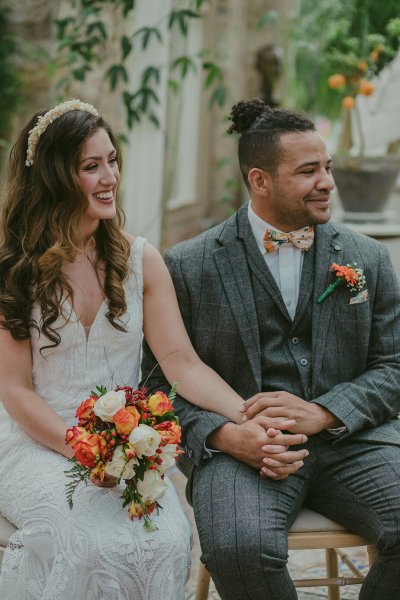 Bride and groom flowers orange roses bouquet sitting holding hands