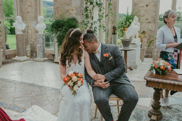 Bride and groom flowers orange roses bouquet sitting holding hands