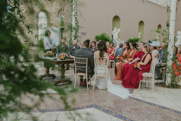 Bride and groom sitting on chairs bridesmaids and guests